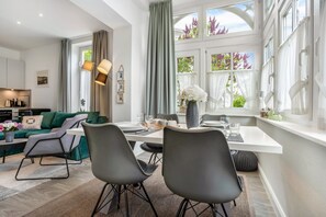 A modern dining area with a white table, grey chairs, and a vase of flowers.