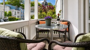 Ein Balkon mit Korbmöbeln, einem runden Tisch und einem Blumentopf.