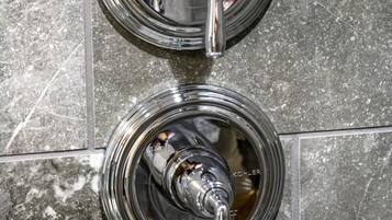 Two chrome-finished faucets with the brand name "Kohler" on a tiled wall.