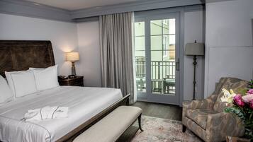 Une chambre d’hôtel avec un grand lit, une banquette, une chaise, une table de chevet et une vue sur l’extérieur grâce à une porte coulissante.