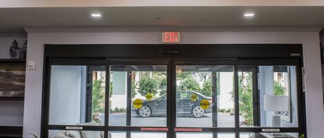 A lobby with a chandelier, a reception desk, and a view of the street outside.
