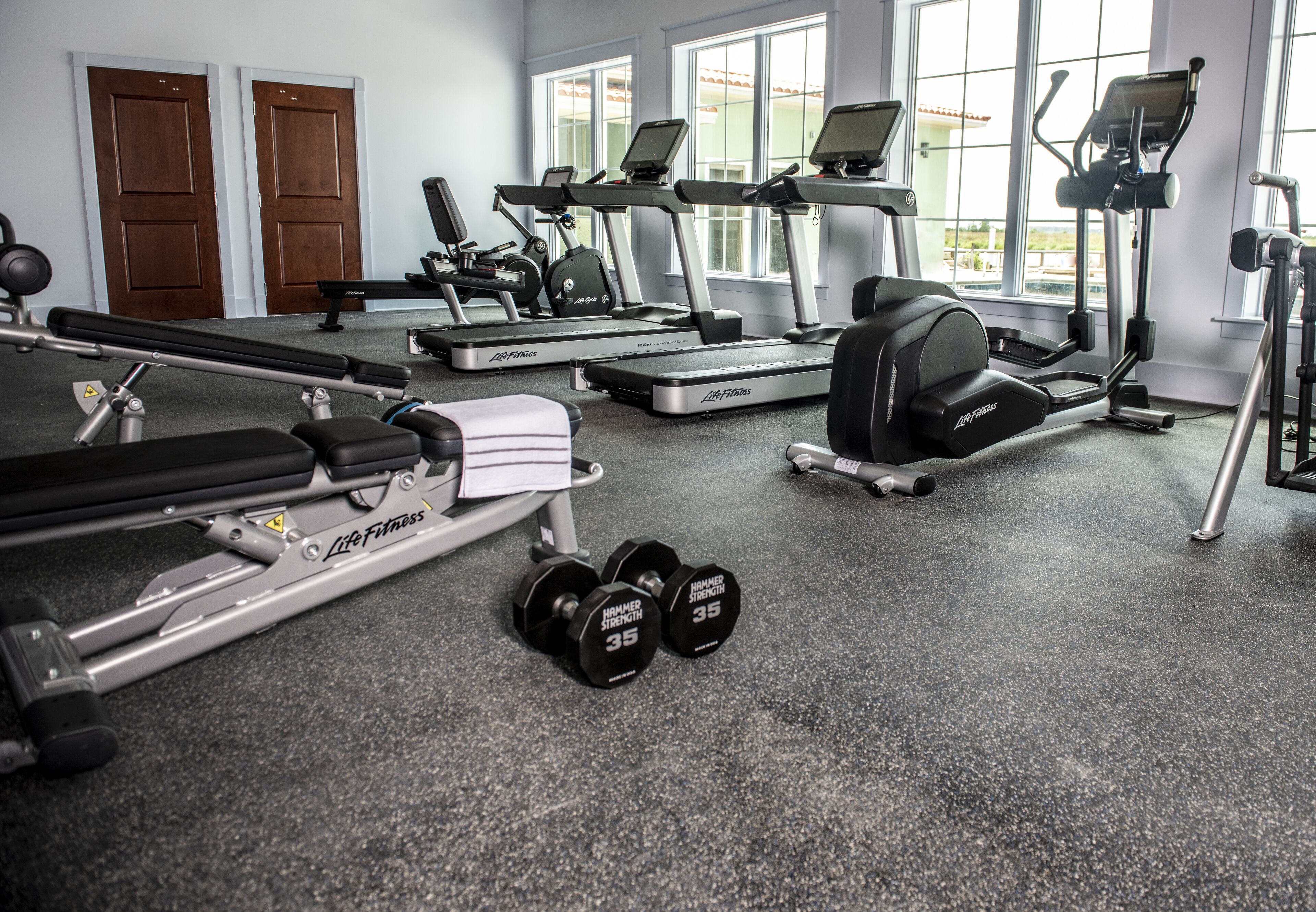 A gym with treadmills, a bench press, and dumbbells.