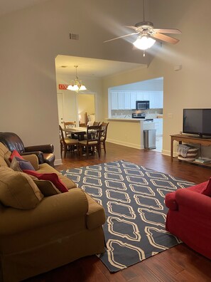 Relax in this open-plan living space with a dining area, featuring a comfortable sofa and a television.