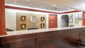 A reception desk at Comfort Inn with a wooden panel wall, a sign, and a door. - Comfort Inn Bristol (Bristol)