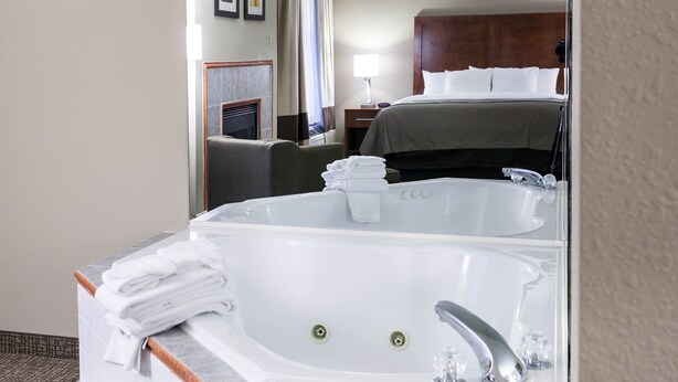 A hotel bathroom with a large white bathtub, a separate sink, and a mirror reflecting the room. - Comfort Inn Bristol (Bristol)