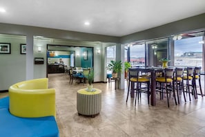 A hotel lobby with a reception desk, dining area with yellow chairs, and a large window offering a view of the outside. - Bristol Arcadia Inn (Bristol)