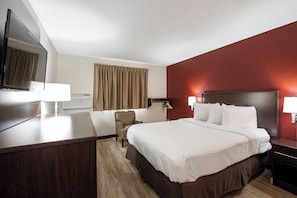 A hotel room with a bed, bedside tables, a desk, a chair, a television, and a window with curtains. - Red Roof Inn Bristol (Bristol)