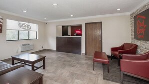 A spacious lobby with a reception desk, a Red Roof Inn sign, and a seating area with red chairs. - Red Roof Inn Bristol (Bristol)