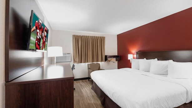 A hotel room with a large bed, a desk, a TV, and a window with curtains. - Red Roof Inn Bristol (Bristol)