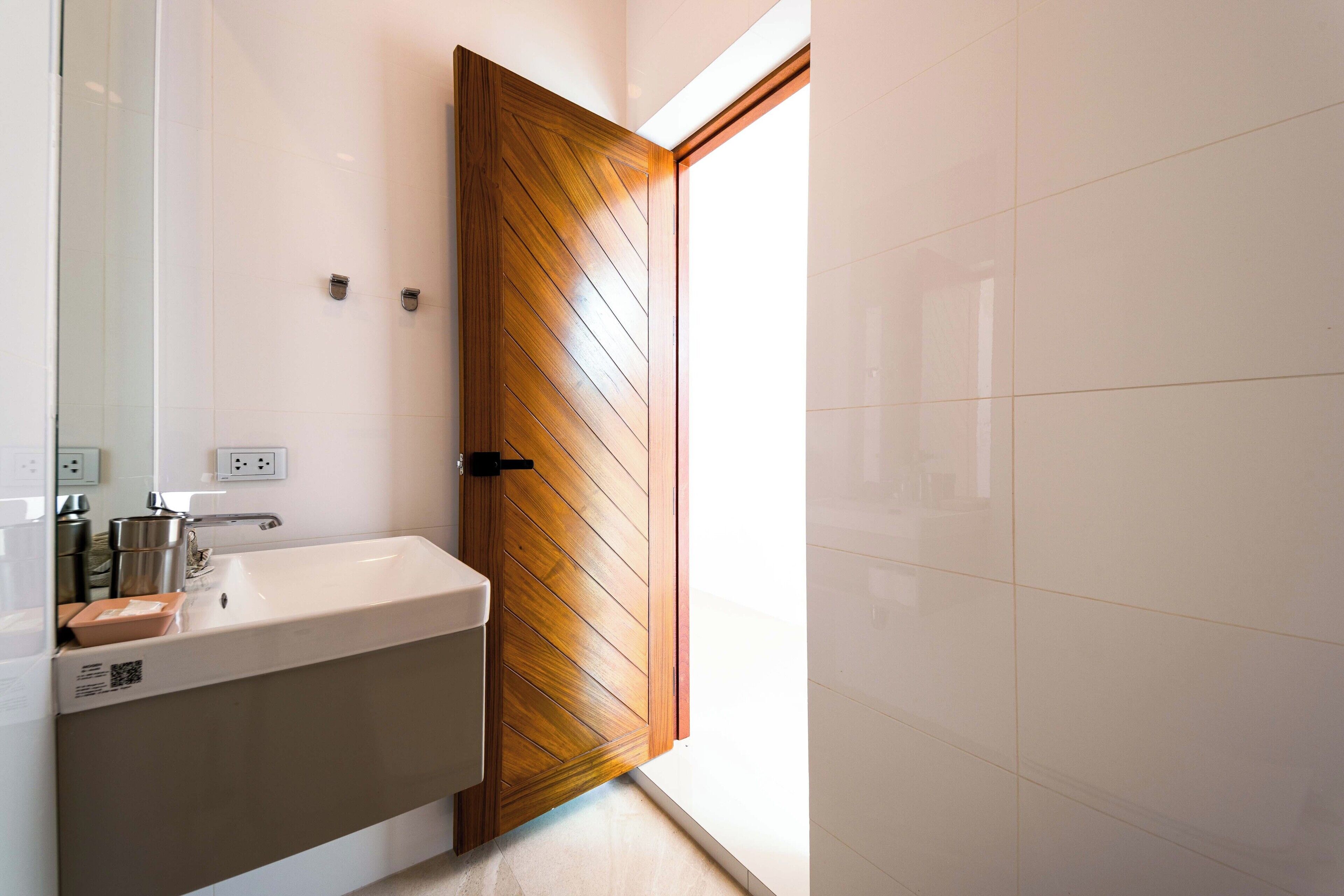 Une salle de bain avec une porte en bois, un lavabo et un miroir.
