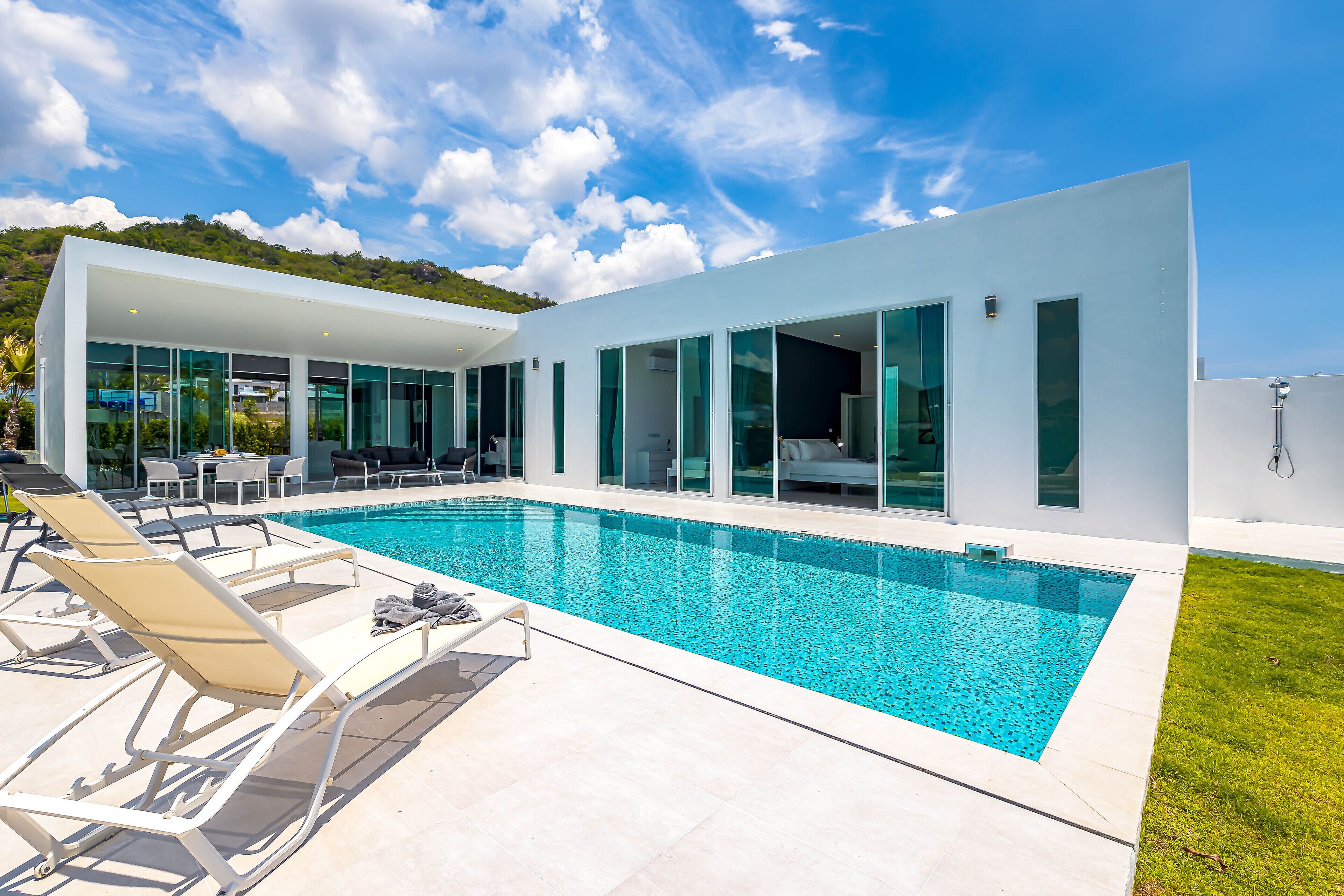 A modern house with a swimming pool, lounge chairs, and a view of the surrounding landscape.