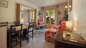 A dining area with a table set for four, a sofa, and a small table with a lamp. - Résidence le Chardonnet G 1BR for 4 w/Shared Pool & panoramic views, Argentière (Chamonix), France (Argentière (Chamonix))