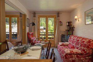 Relax in a well-appointed room with a dining area and seating area, featuring a table for two and a comfortable sofa.