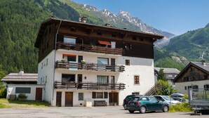 A multi-story building with balconies, a parking area, and a mountainous backdrop. - Résidence le Chardonnet G 1BR for 4 w/Shared Pool & panoramic views, Argentière (Chamonix), France (Argentière (Chamonix))