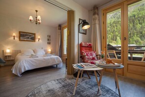 Relax in this serene hotel room with a large bed, bedside tables, and a stunning forest view.
