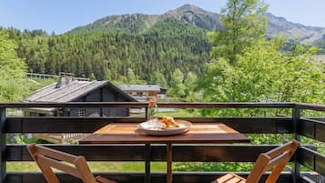 Een houten terras met een tafel en stoelen, met uitzicht op een bergachtig landschap.