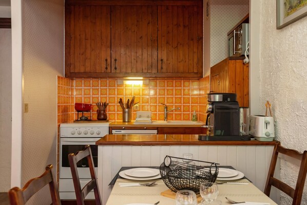 Cozinha com armários de madeira, fogão e cafeteira.