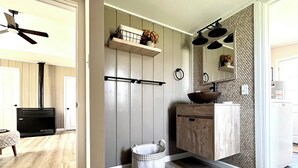 A modern kitchen with wooden cabinets, a black stove, and a hanging pot rack. - Cozy cabin retreat in rustic setting. Private lake, bonfire under the stars! (Lake)