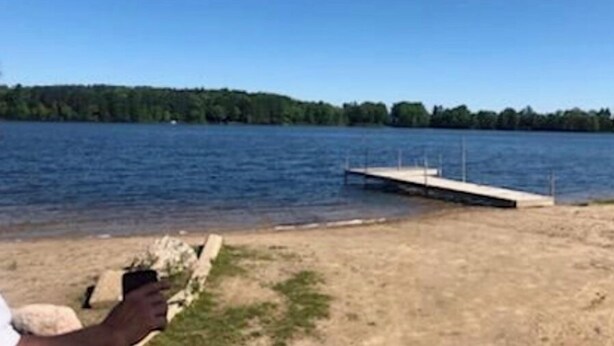 A lake with a dock extending into the water. - Cozy cabin retreat in rustic setting. Private lake, bonfire under the stars! (Lake)