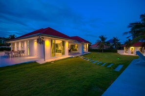 Une maison moderne avec un toit rouge, de grandes fenêtres et une pelouse bien entretenue.