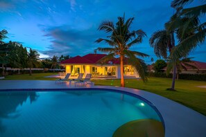A swimming pool with lounge chairs, a house with a red roof, and palm trees. - Amazing 6 Bedroom Pool Villa ED60 (Hua Hin)