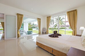 Une chambre d’hôtel moderne dotée d’un grand lit, d’une porte vitrée donnant sur un balcon et offrant une vue sur l’extérieur.