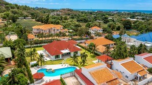 Un quartier résidentiel avec des maisons, une piscine et une vue sur la mer.