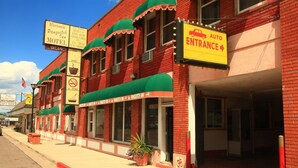 A red brick building with a green awning, signs for a motel and a restaurant, and a clear blue sky. - Panguitch Inn Motel (Panguitch)