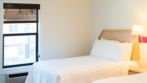 A hotel room with two beds, a ceiling fan, a window with a view of buildings, and a bedside table with a lamp. - Panguitch Inn Motel (Panguitch)