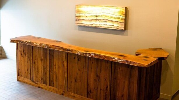 A reception desk with a wooden finish, a wall-mounted artwork, and a tiled floor. - Panguitch Inn Motel (Panguitch)