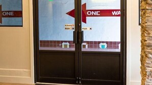 A hotel entrance with a glass door marked 'EXIT' and 'ONE WAY' signs, a doormat, and a stone pillar. - Panguitch Inn Motel (Panguitch)