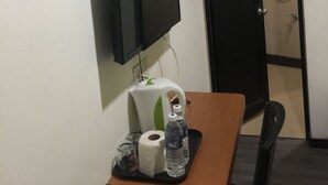 A hotel room with a flat-screen TV mounted on the wall, a door with a shower, and a table with toiletries and a bottle of water. - Permai Hotel Sibu (Sibu)