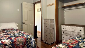 Une chambre avec deux lits, une commode et une armoire.