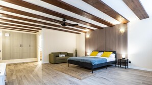 Un dormitorio con cama, sofá, armario y ventilador de techo.