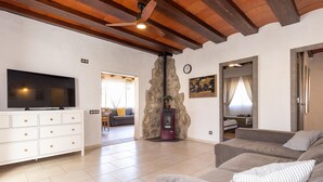 Una sala de estar moderna con un televisor de pantalla plana, una chimenea de piedra, un sofá y un comedor al fondo.
