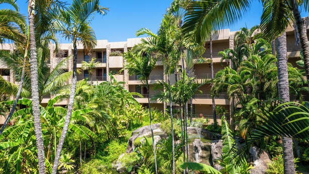 Ein Hotel mit mehreren Balkonen, üppiger tropischer Vegetation und einem Felswasserfall.