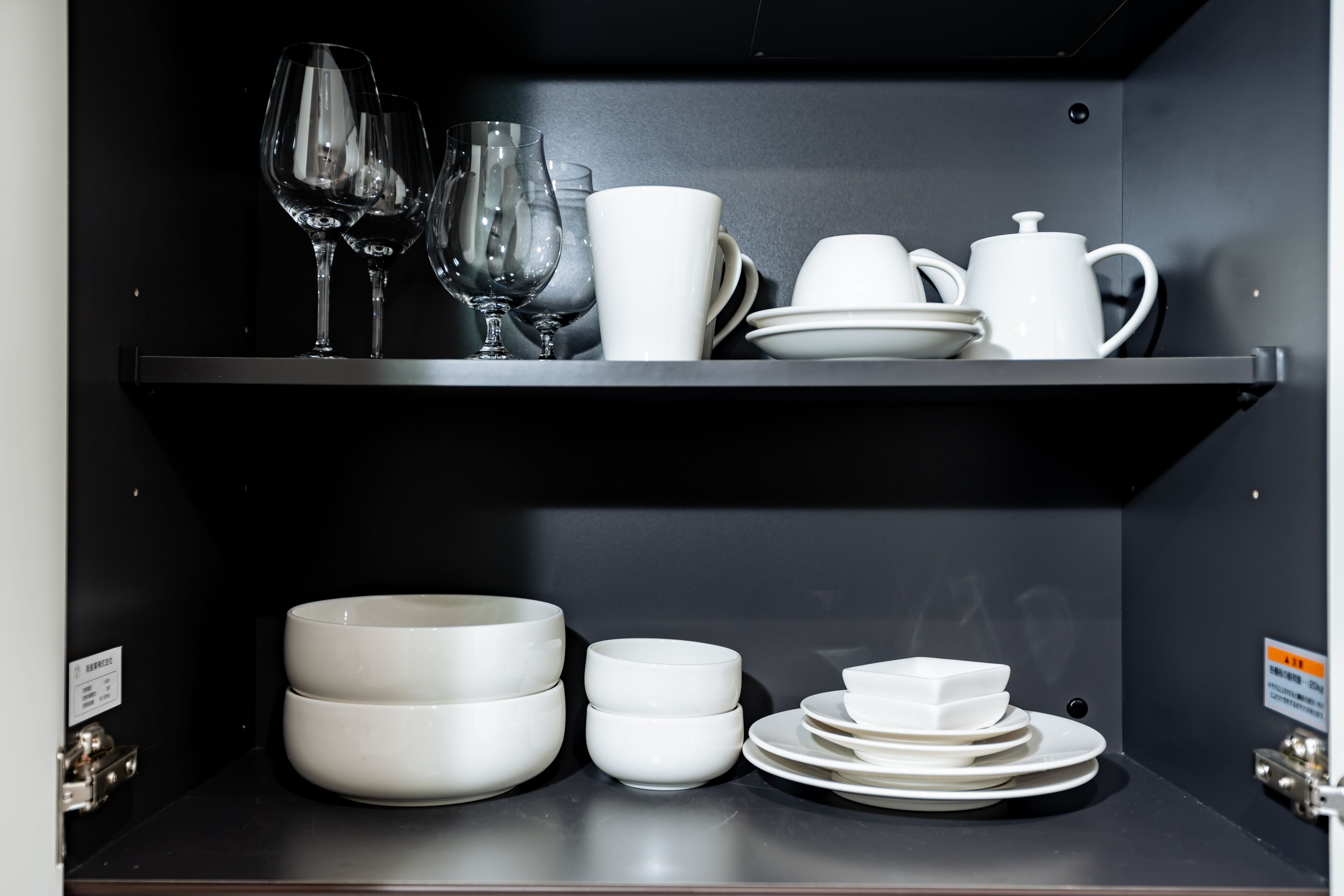 A black shelf with white dishes and glasses.