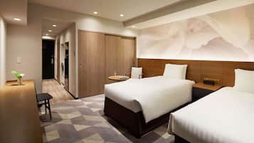 A hotel room with a large bed, a bedside table, a chair, a small table with a glass of wine, and a wall-mounted artwork.