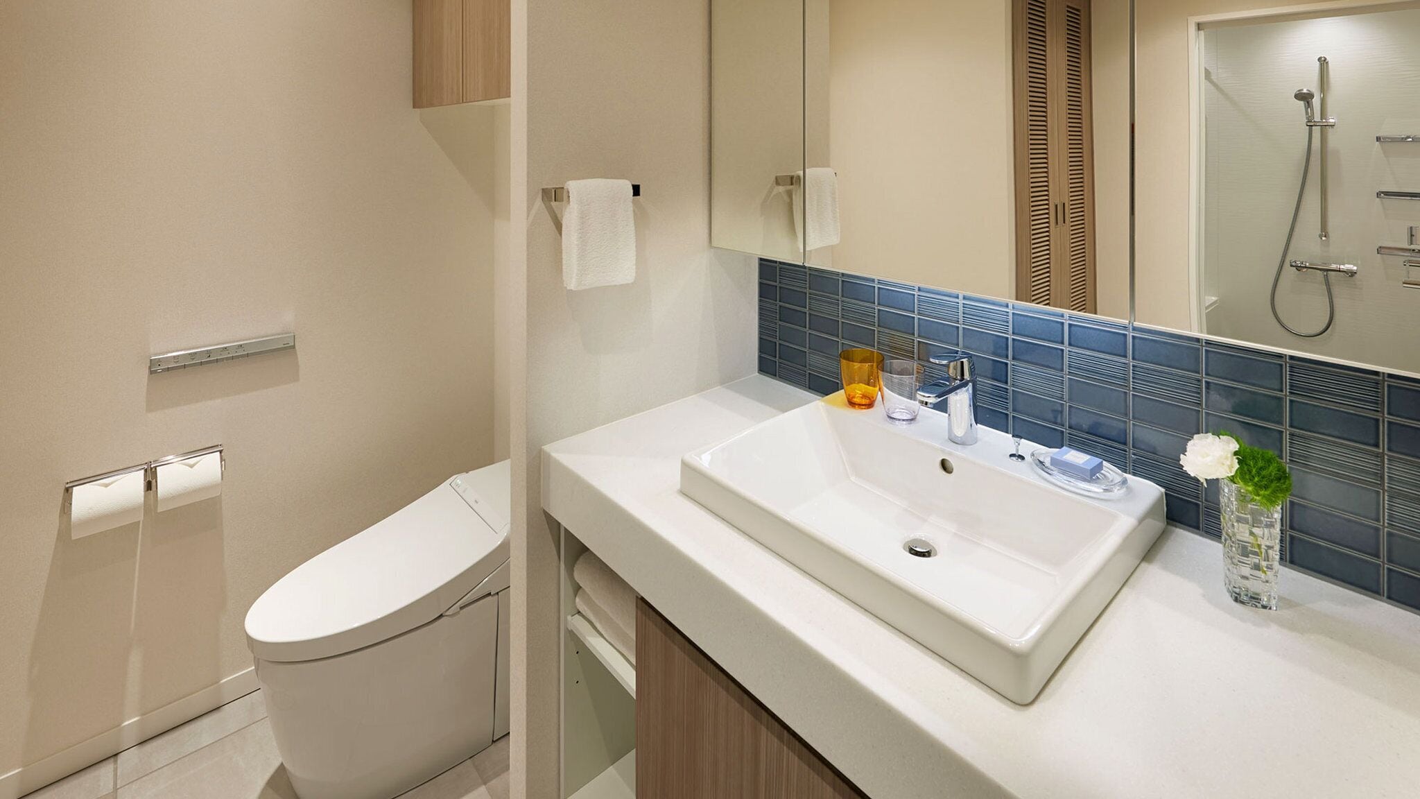 A modern bathroom with a white toilet, a sink with a mirror above it, and a shower area.