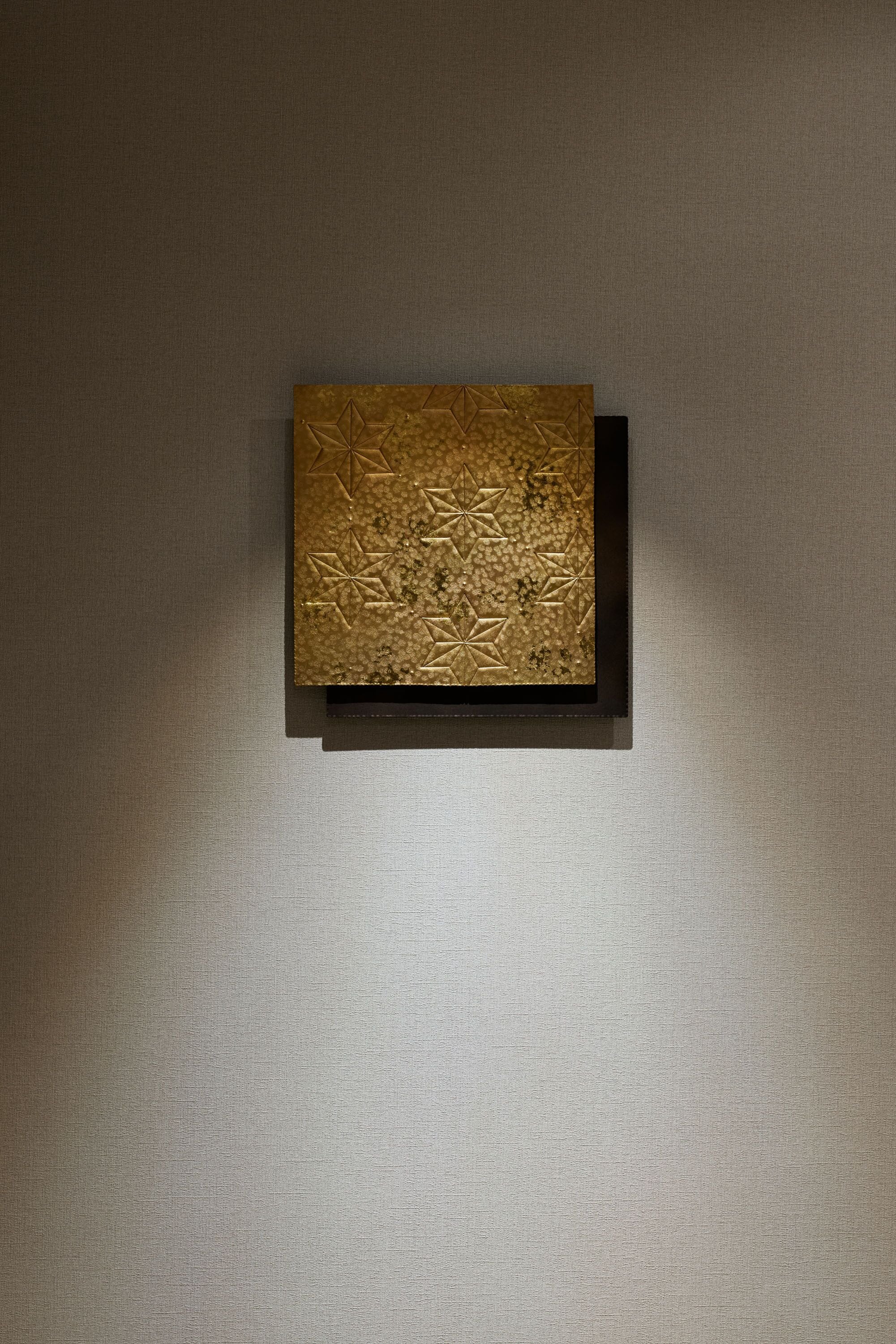 A textured wall with a framed object.