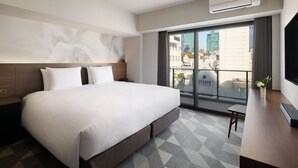 Een moderne hotelkamer met een groot bed, een bureau, een flatscreen-televisie en een balkon met uitzicht over de stad.