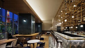 Een moderne bar met een lange toonbank, diverse zitmogelijkheden en uitzicht op de Eiffeltoren 's nachts.