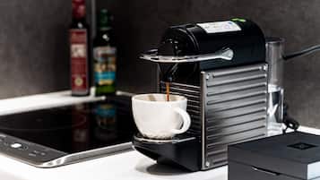 Una cafetera sirviendo café en una taza sobre una encimera de cocina.