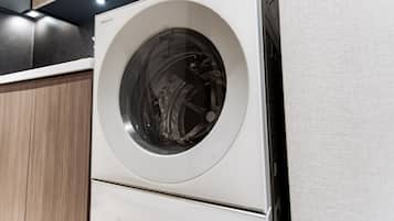 Une vue de face d’un lave-linge blanc orné du logo Panasonic, placé devant un meuble en bois.