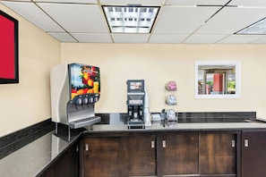 A coffee station with a fruit juice dispenser, a coffee machine, and a clock on the wall. - RED Roof INN Berea (Berea)