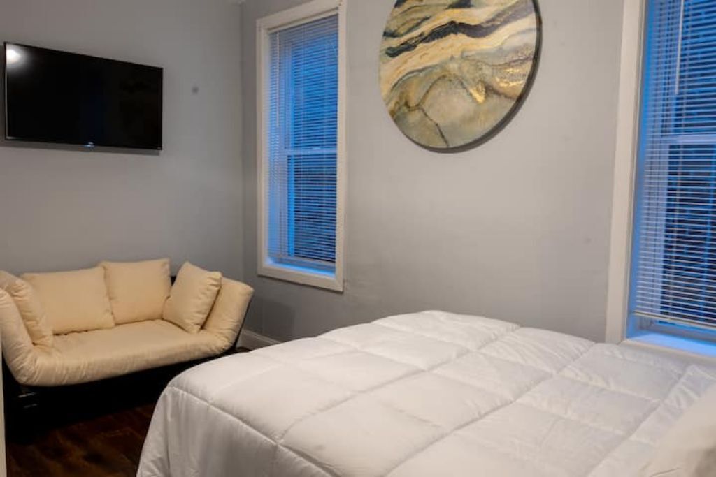 Ein Schlafzimmer mit Bett, Sofa, Fernseher und Wandbild.