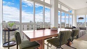 Un espace de restauration moderne, doté d’une grande table, de nombreuses chaises et offrant une vue sur le paysage urbain grâce à de larges fenêtres.