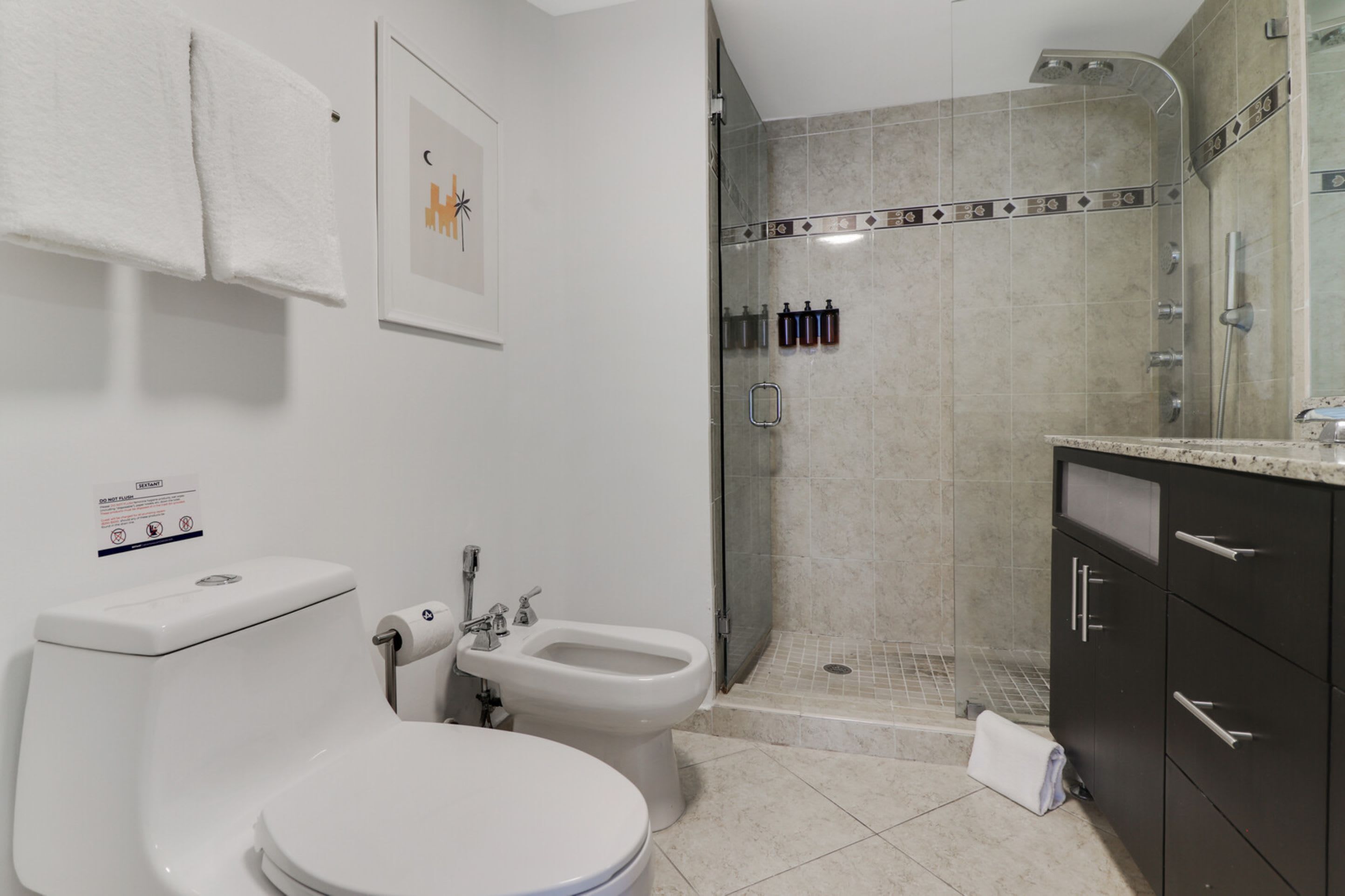 Et badeværelse med toilet, bidet og bruseniche.