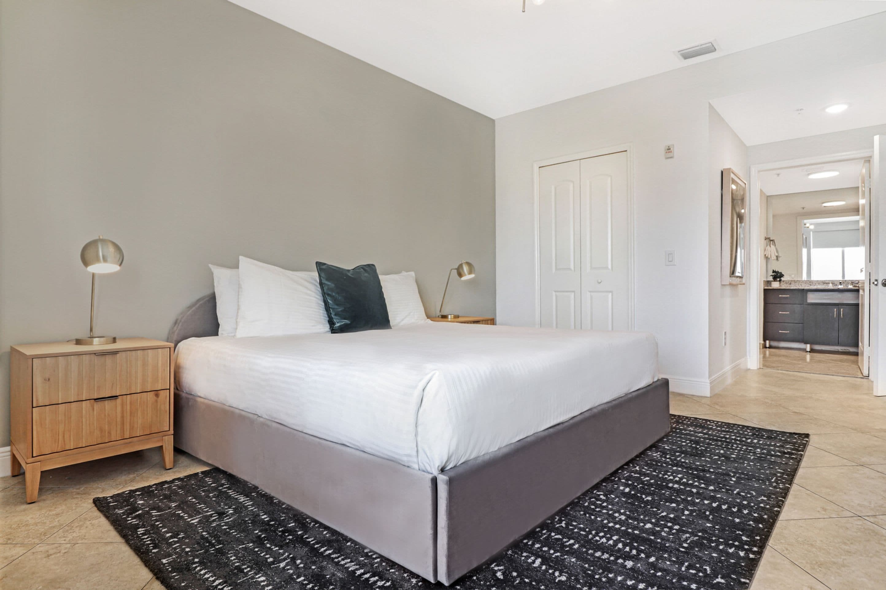 Un dormitorio moderno con una cama grande, mesitas de noche y un tapete negro estampado.