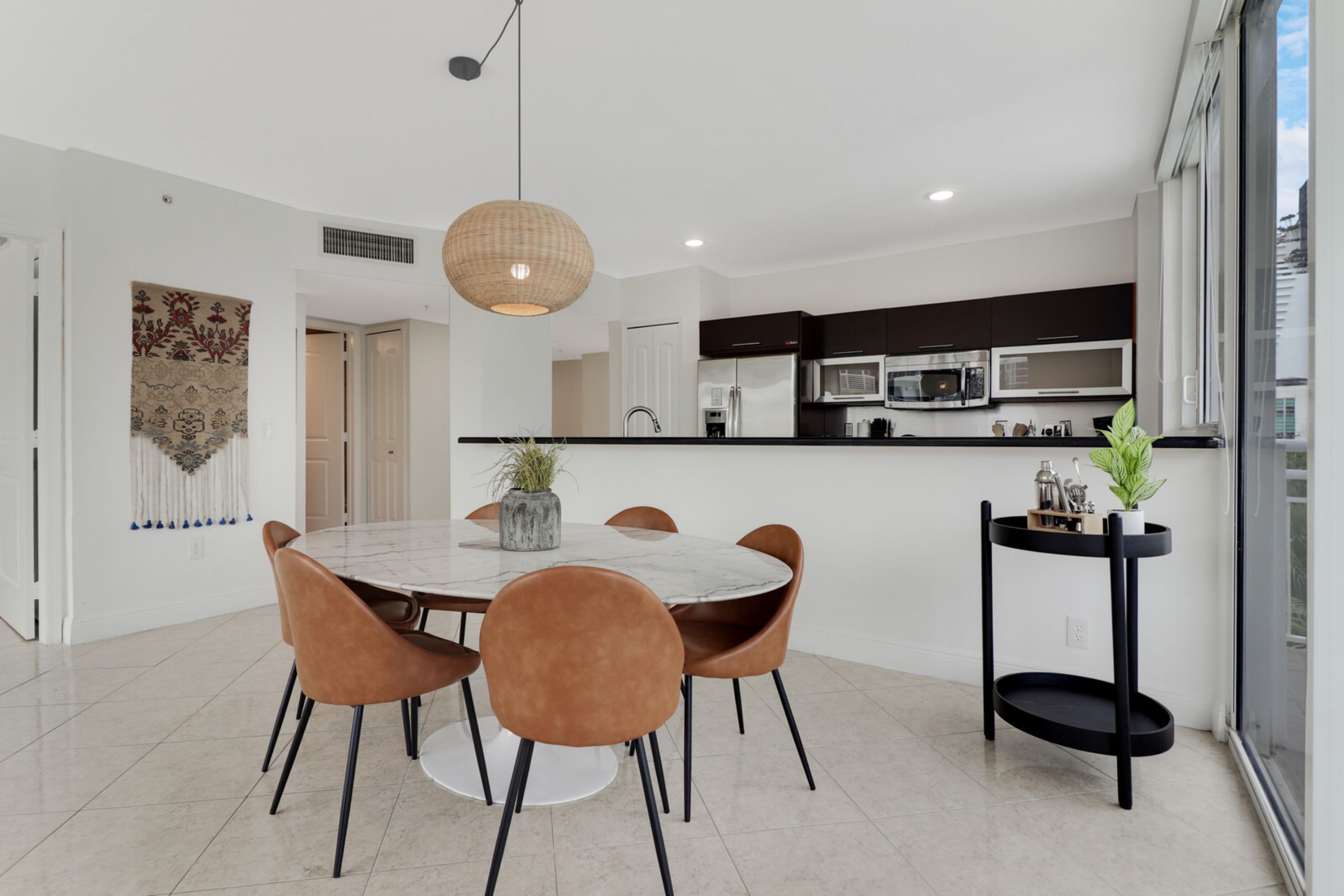 A modern kitchen with dark cabinets, stainless steel appliances, and a black island.